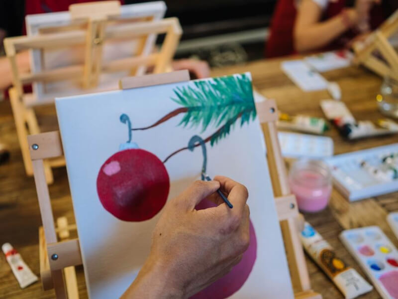 Close up on hands painting a Christmas bauble on canvas